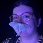 Woman at night with luna moth on her face